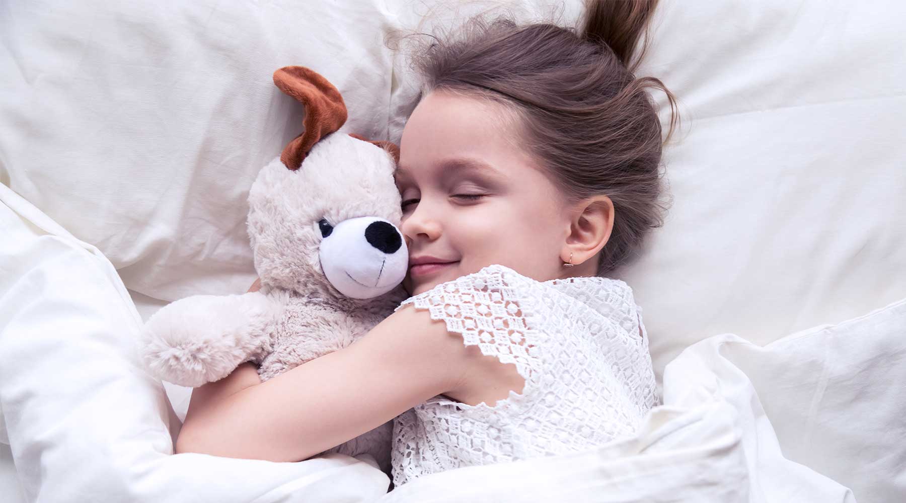 smartsleep Kinder-Schlaf: Kleines Mädchen schläft mit Kuscheltier im Arm